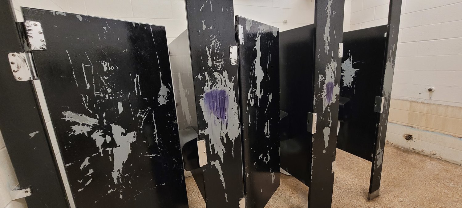 Stall doors in the boys' restroom at Royal Junior High School are marred with years of graffiti which has been painted over multiple times but is peeling.